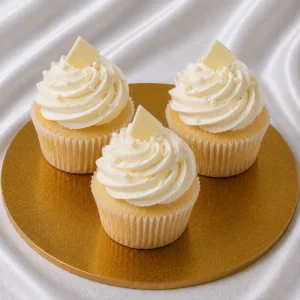 Set of vanilla cupcakes with ivory-white frosting and cream swirls on a bakery surface
